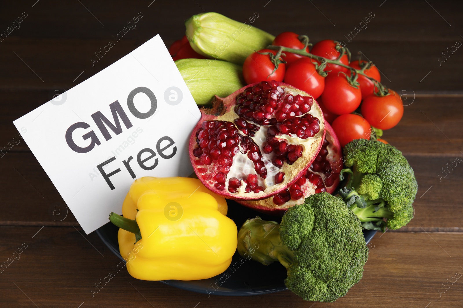 Photo of Tasty fresh GMO free products and paper card on wooden table