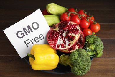 Photo of Tasty fresh GMO free products and paper card on wooden table