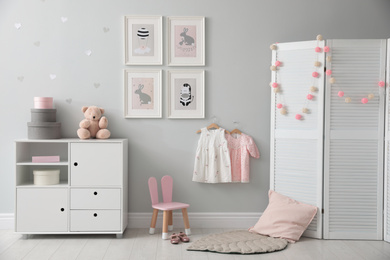 Stylish baby room interior with chest of drawers and cute pictures on wall