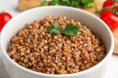 Bowl of buckwheat porridge with parsley on table, closeup