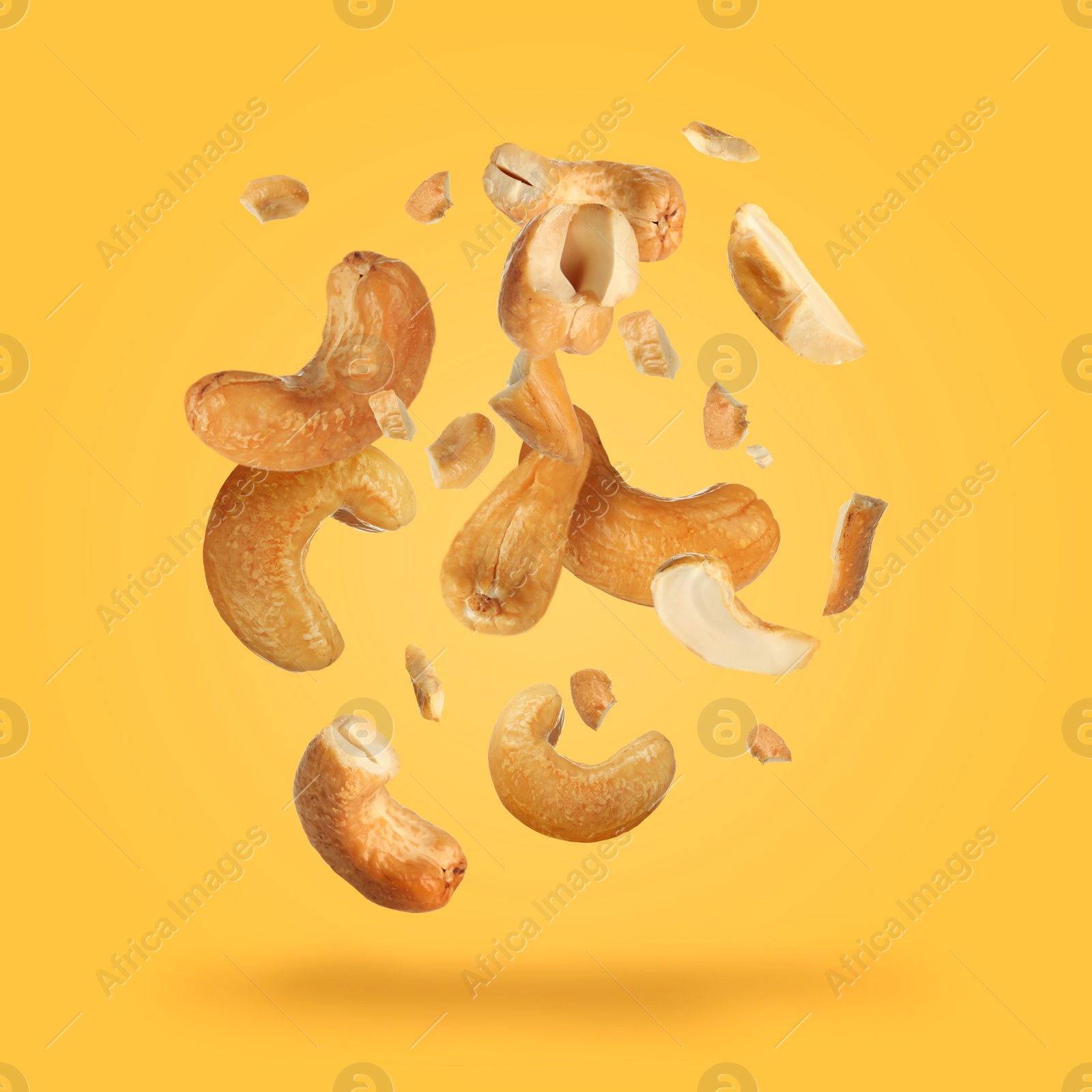 Image of Tasty cashew nuts flying on yellow background