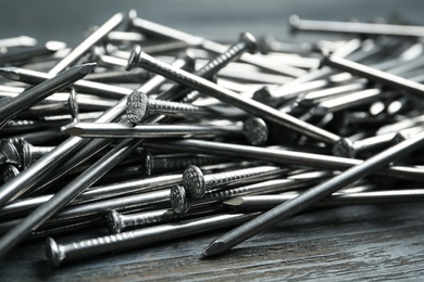 Photo of Many metal nails on wooden background, closeup