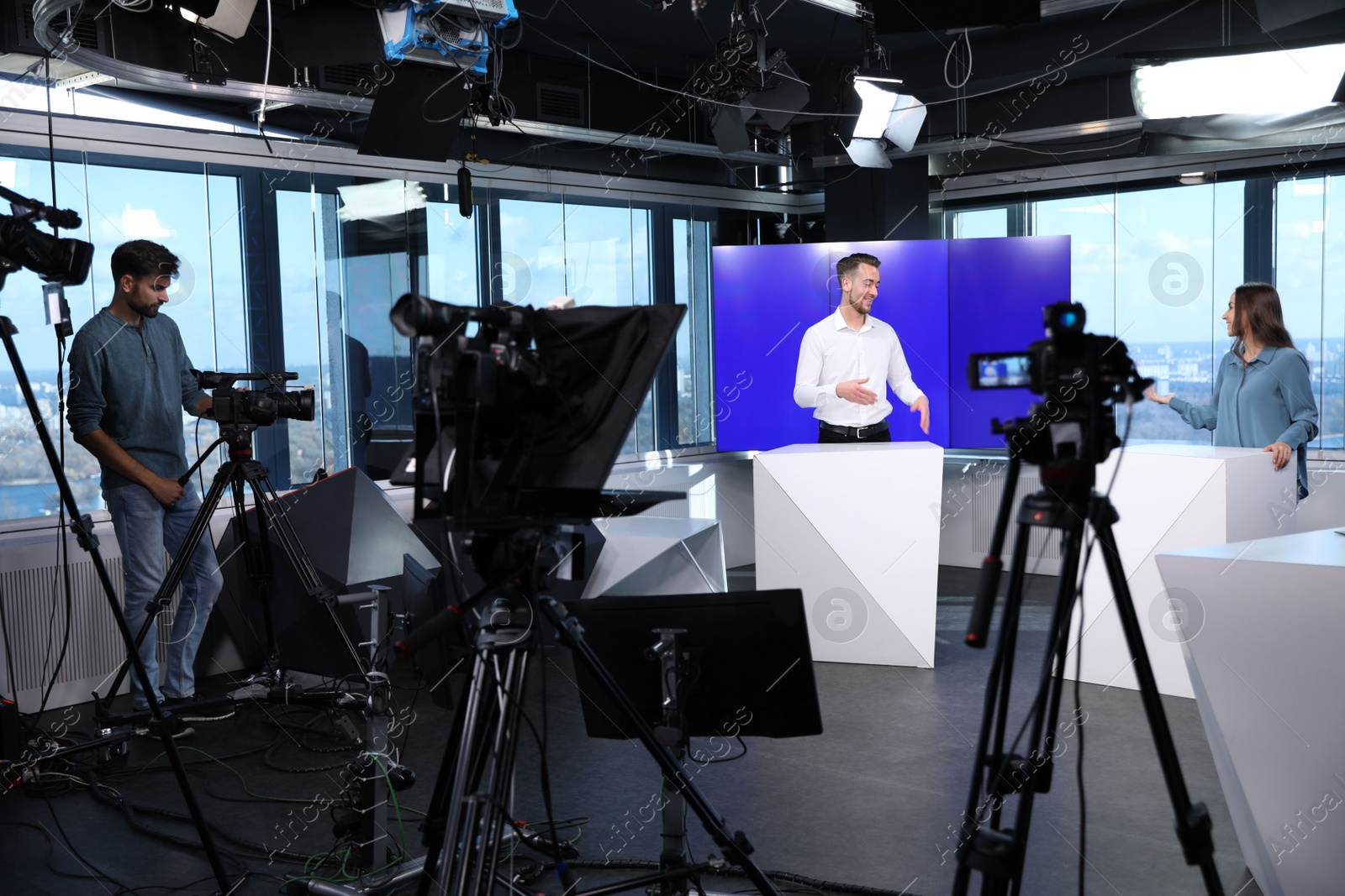 Photo of Presenters and video camera operator working in studio. News broadcasting