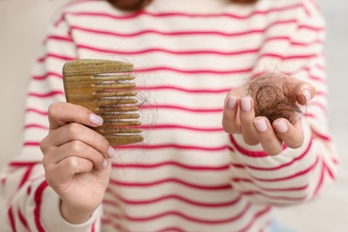 Photo of Woman holding comb with lost hair, closeup. Alopecia problem