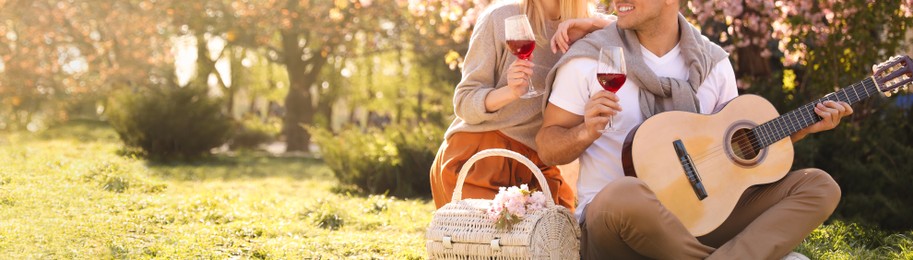 Lovely couple having picnic in park on sunny spring day, closeup view with space for text. Banner design
