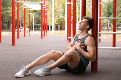 Young man having heart attack on sports ground