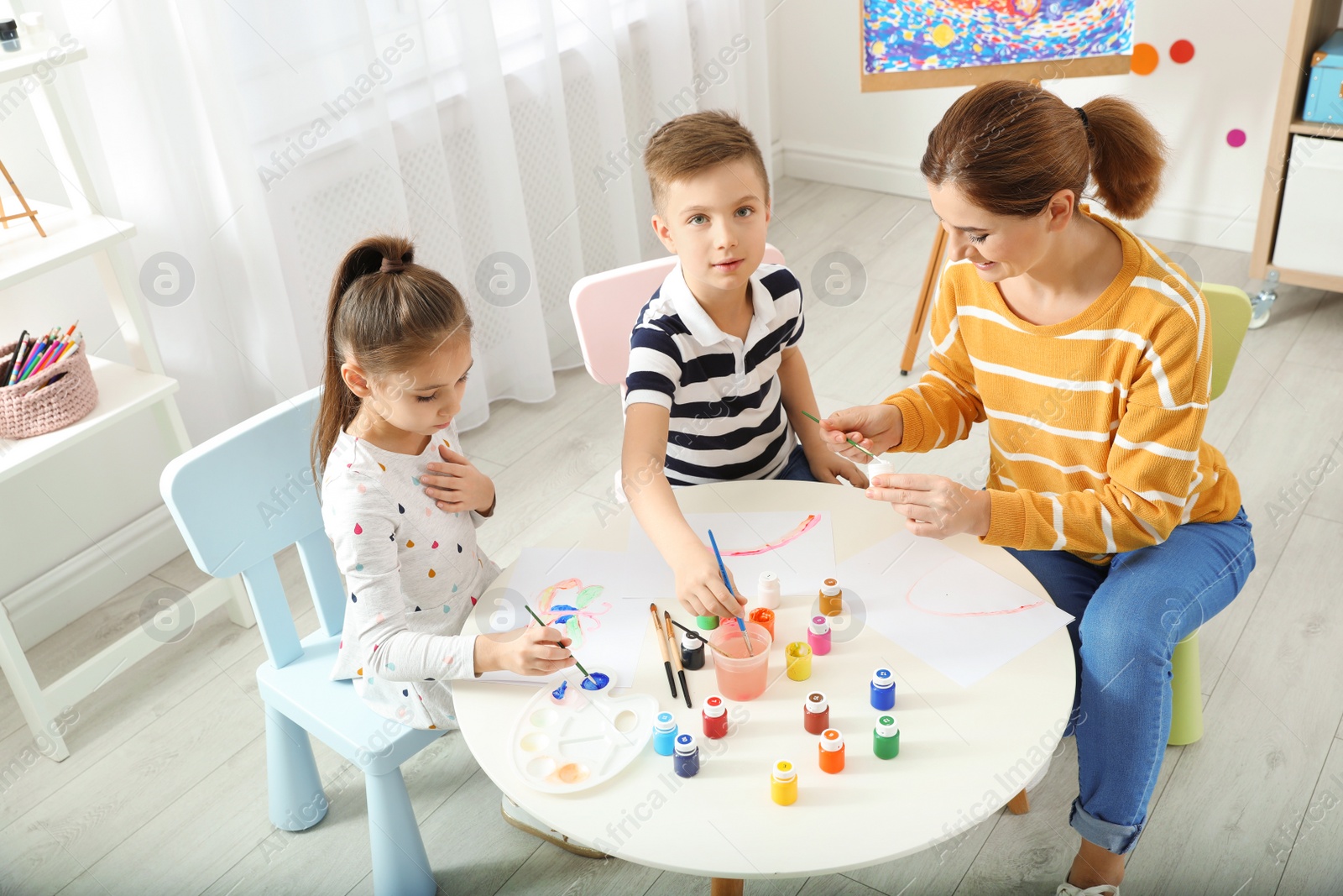 Photo of Children with female teacher at painting lesson indoors