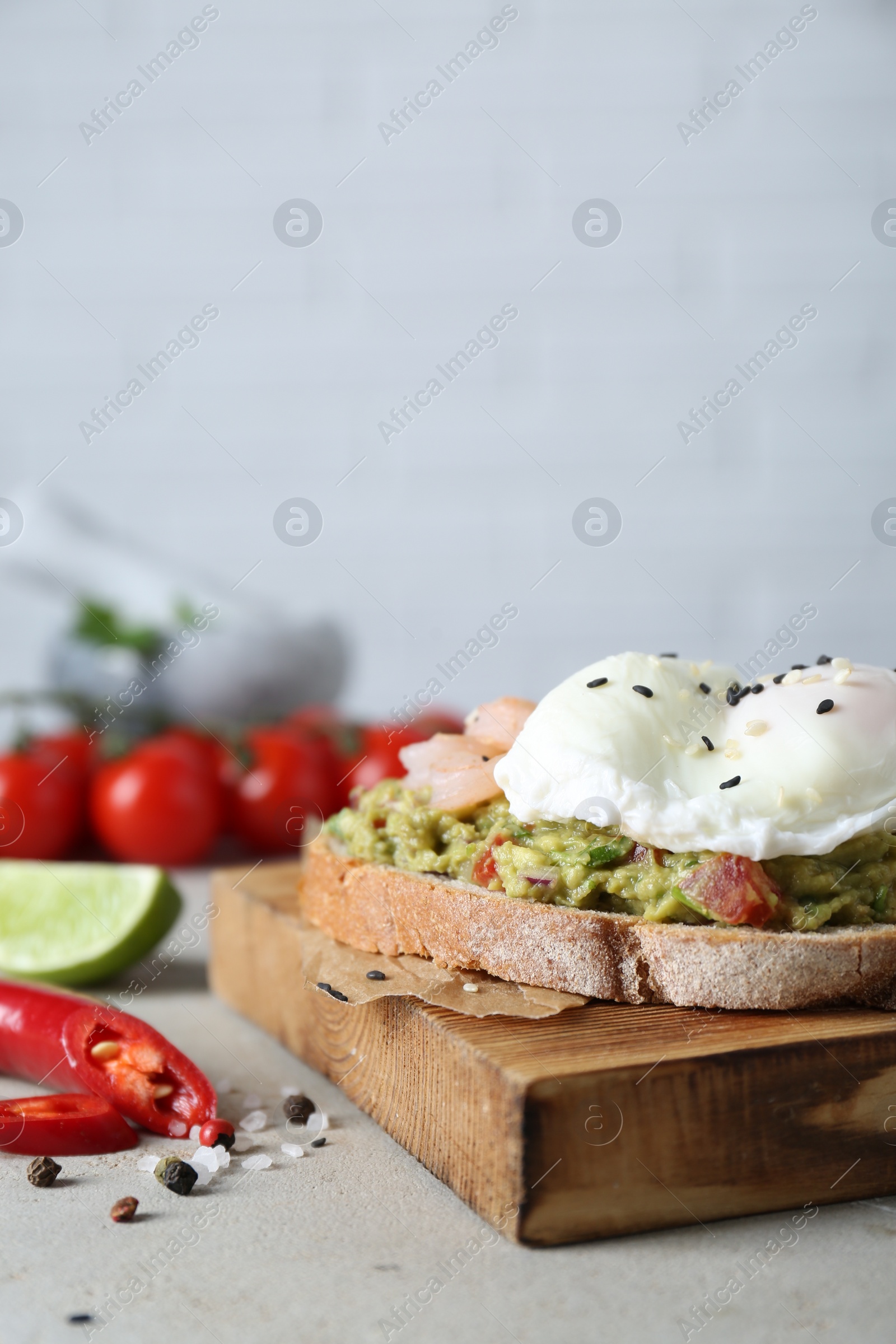 Photo of Delicious sandwich with guacamole, shrimps and fried egg on light grey table, closeup. Space for text