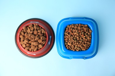 Photo of Dry pet food in feeding bowls on light blue background, flat lay