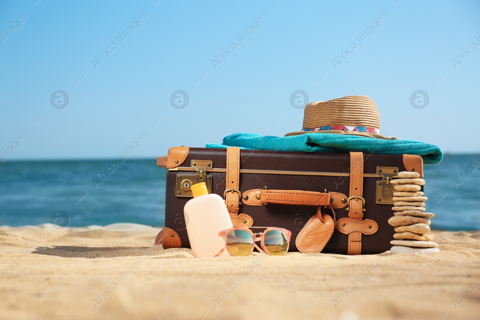 Photo of Suitcase and beach accessories on sand near sea. Space for text