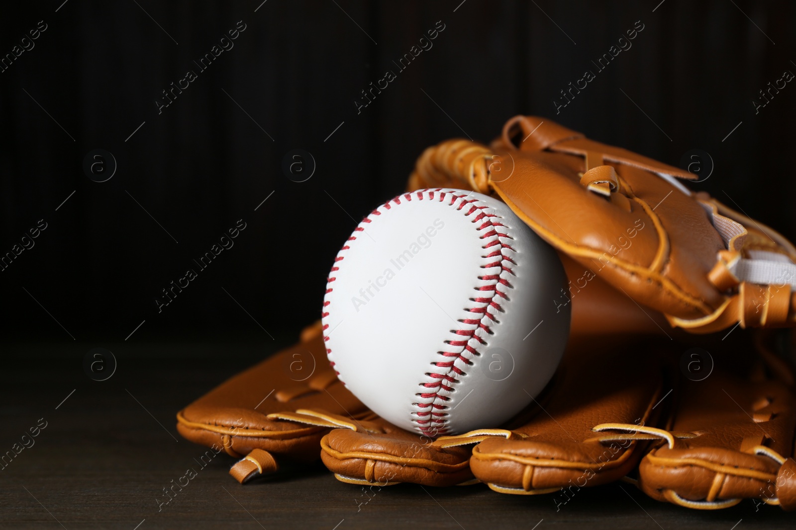 Photo of Leather baseball glove with ball on wooden table, closeup. Space for text