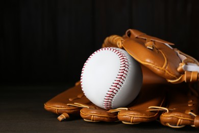 Leather baseball glove with ball on wooden table, closeup. Space for text