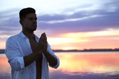 Man near river at sunset, space for text. Nature healing power