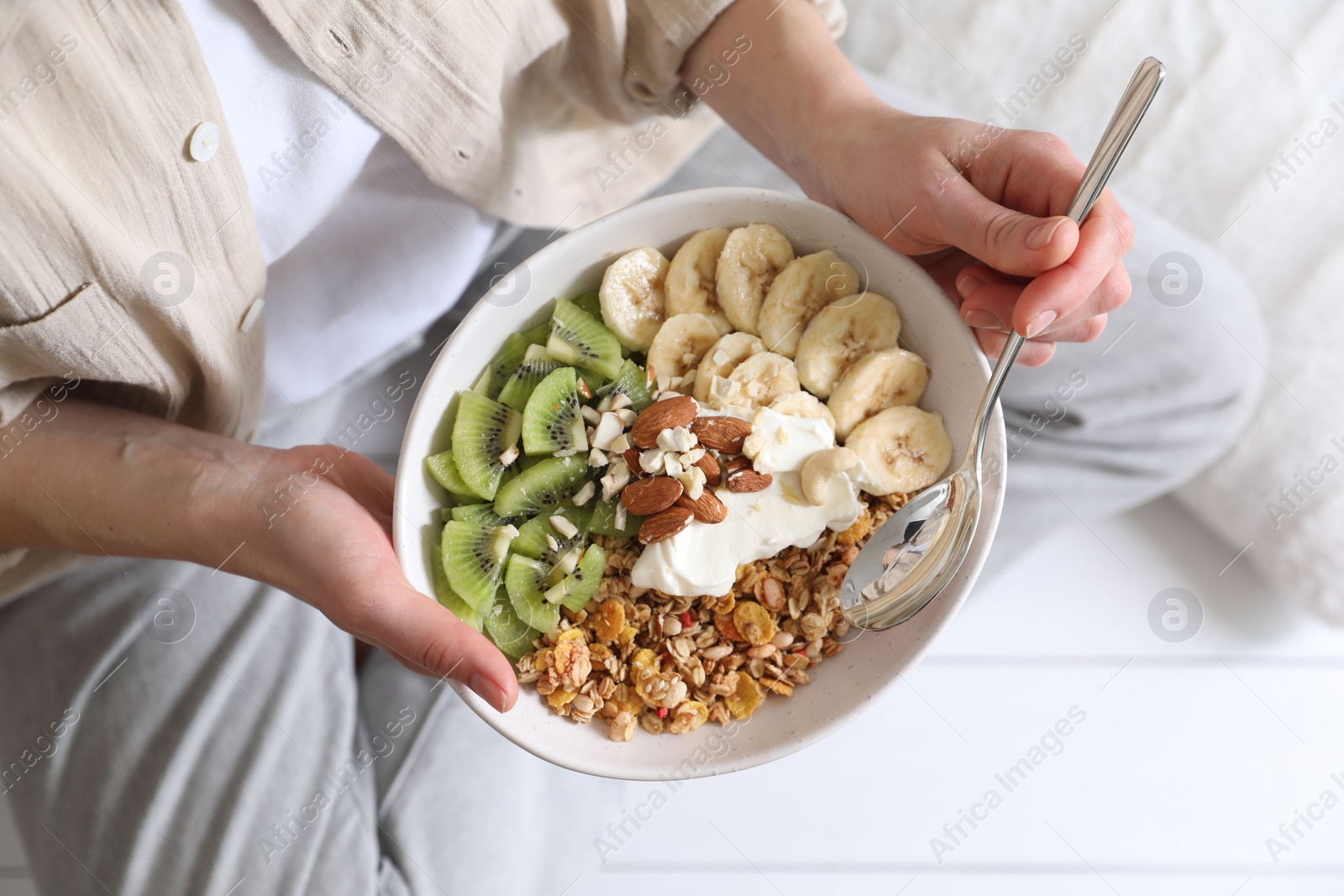 Photo of Woman eating tasty granola indoors, top view