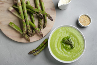 Photo of Delicious asparagus soup served on grey table, flat lay