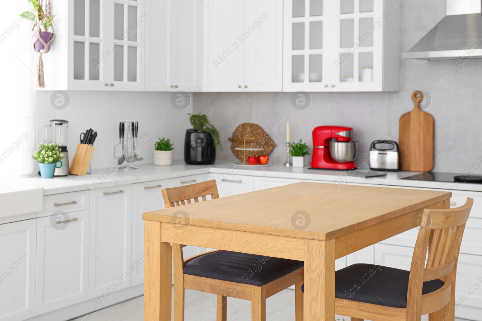 Photo of Stylish wooden table with chairs in kitchen. Interior design