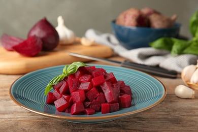 Plate of cut boiled beets with basil on wooden table