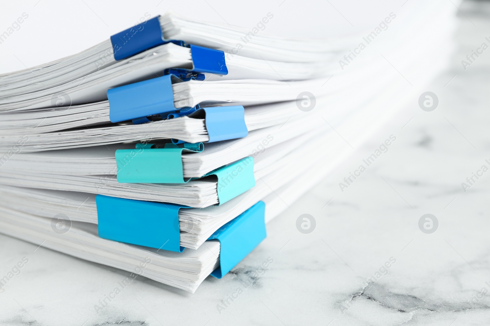 Photo of Stack of documents with binder clips on marble table, closeup