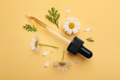 Photo of Flat lay composition with chamomile flowers and pipette of essential oil on color background