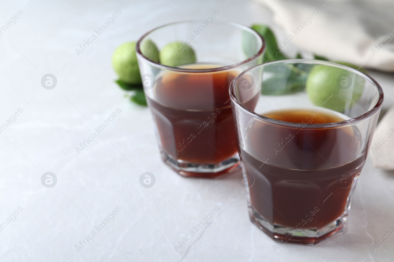 Photo of Delicious liqueur and fresh walnuts on light table, closeup. Space for text