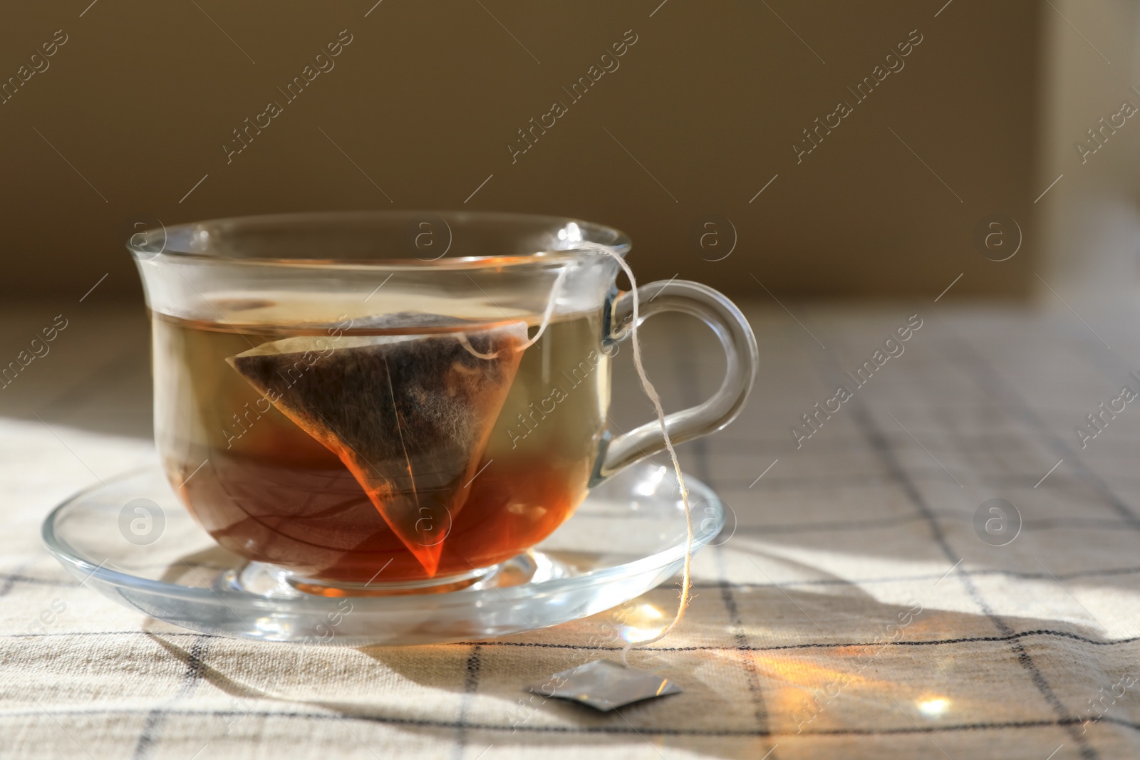 Photo of Tea bag in glass cup on table, closeup. Space for text