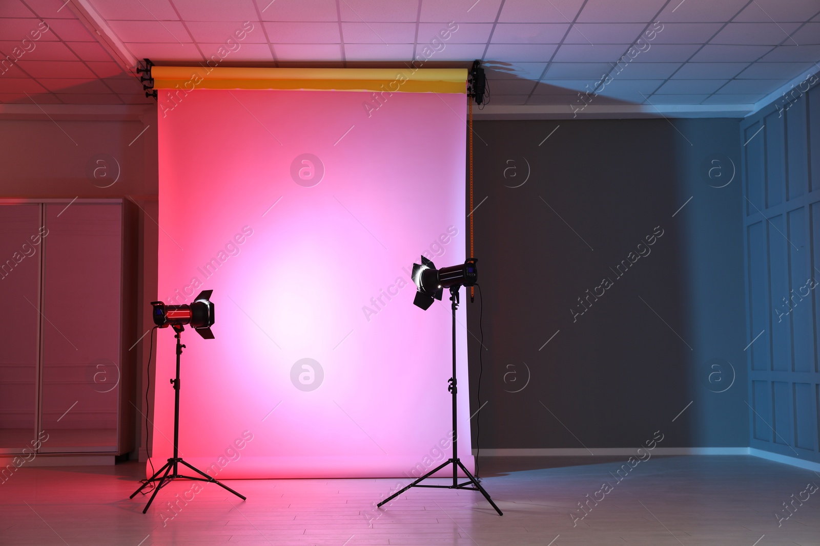 Photo of Photo background in neon lights and professional lighting equipment inside modern studio, space for text