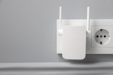 Photo of Wireless Wi-Fi repeater on light grey wall, space for text