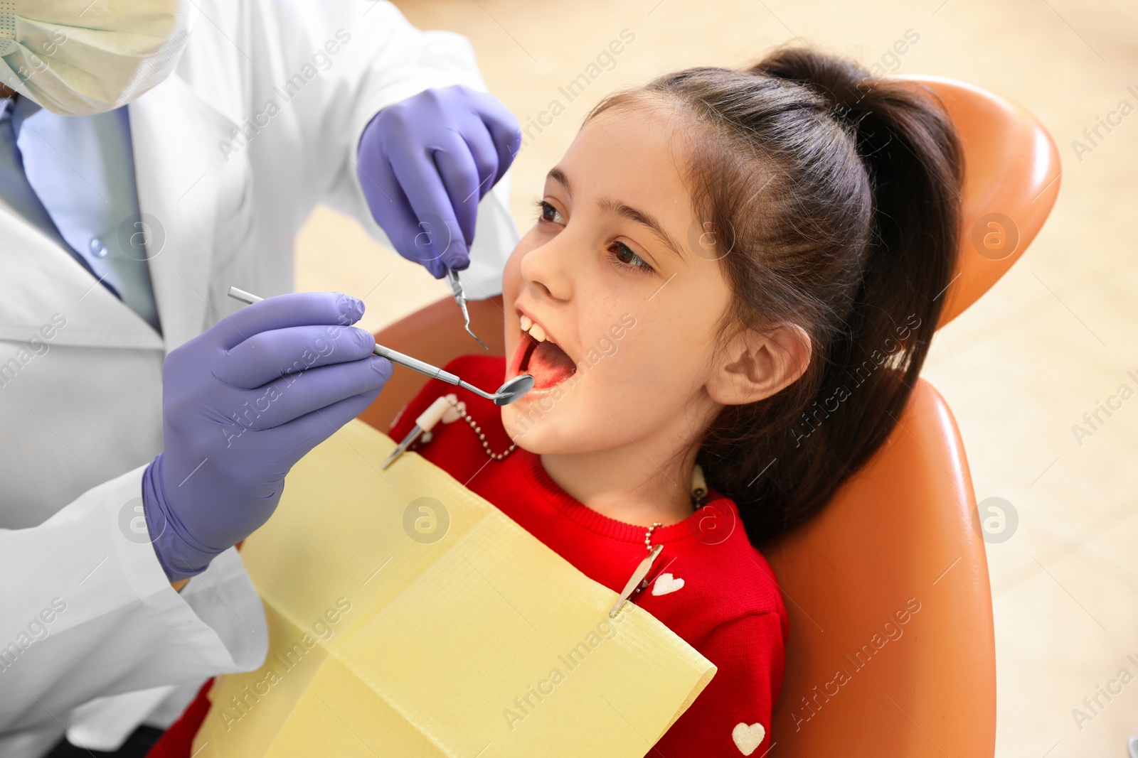 Photo of Professional dentist working with little patient in modern clinic