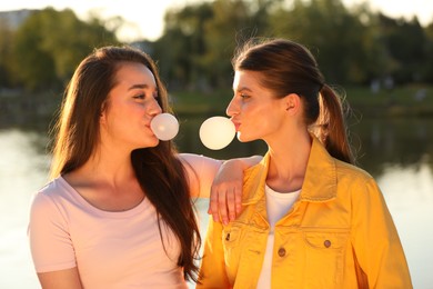 Beautiful young women blowing bubble gums outdoors