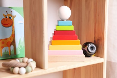 Small camera hidden among toys on wooden shelf in baby room