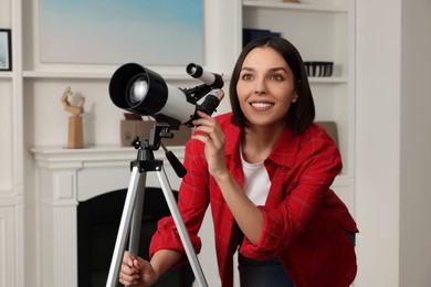 Photo of Beautiful woman using telescope to look at stars in room