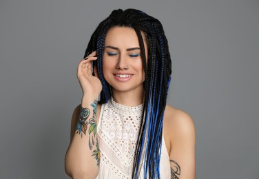 Photo of Beautiful young woman with nose piercing and dreadlocks on grey background