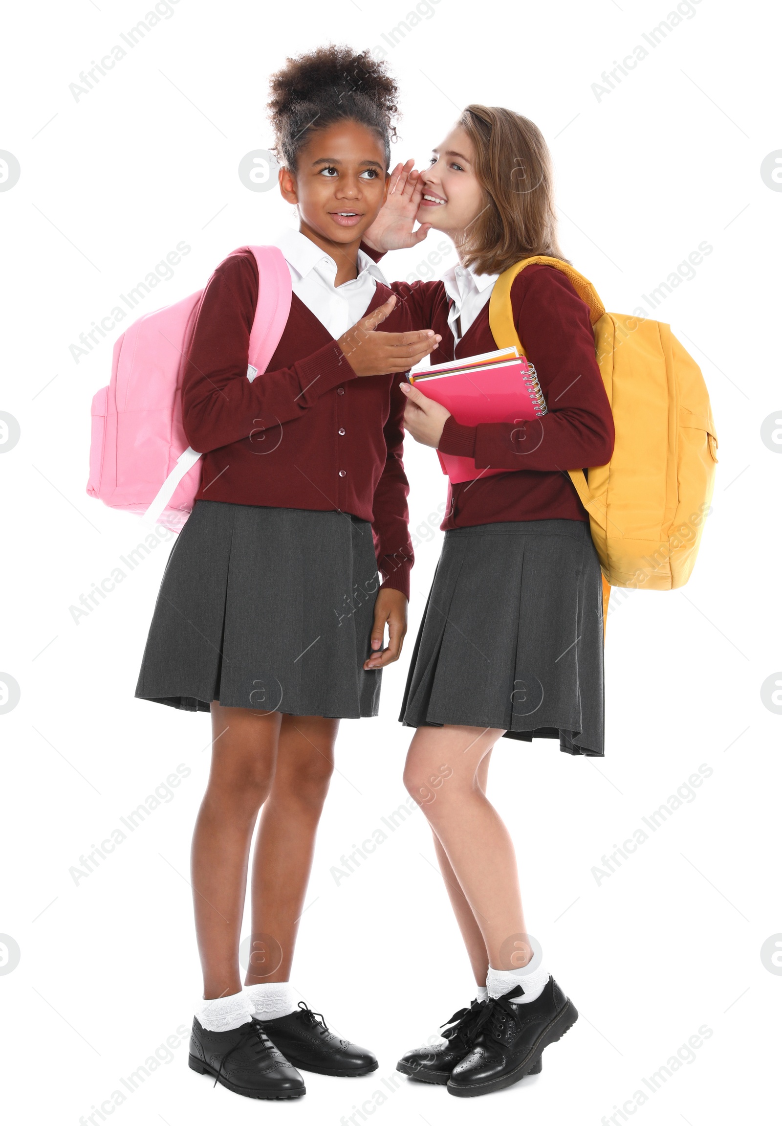 Photo of Happy girls in school uniform gossiping on white background