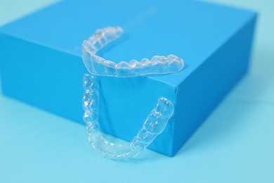 Photo of Transparent dental aligners on light blue background, closeup