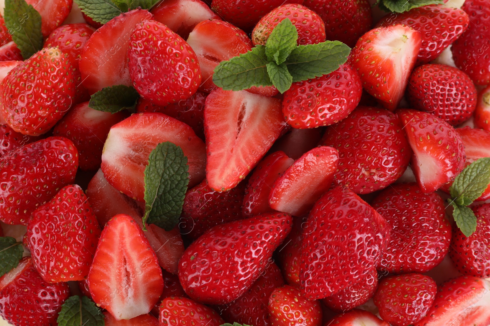 Photo of Many ripe strawberries and mint as background, top view