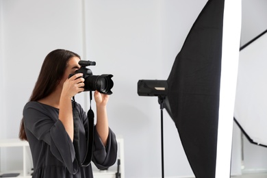Young woman with professional camera in photo studio