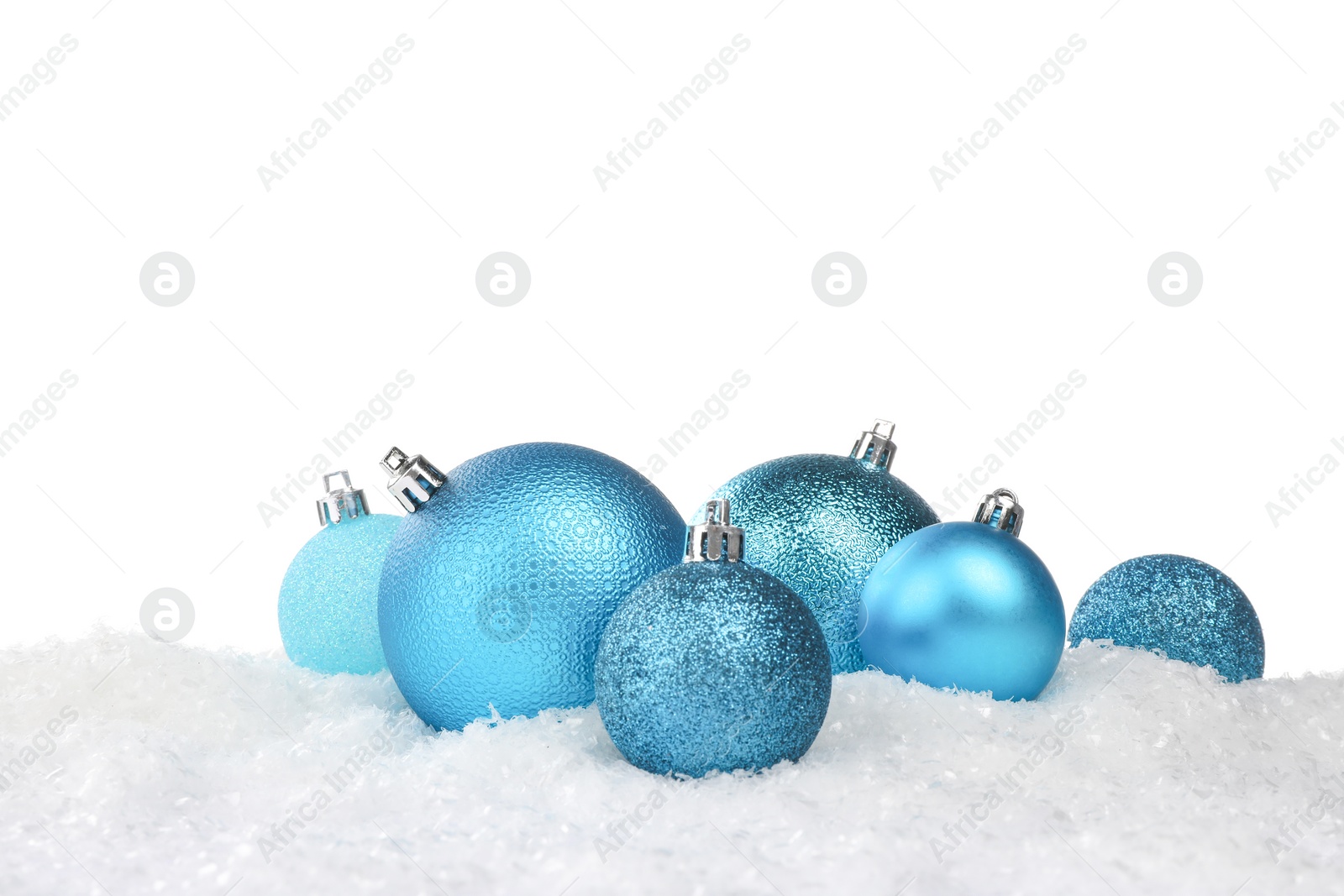 Photo of Beautiful light blue Christmas balls on snow against white background