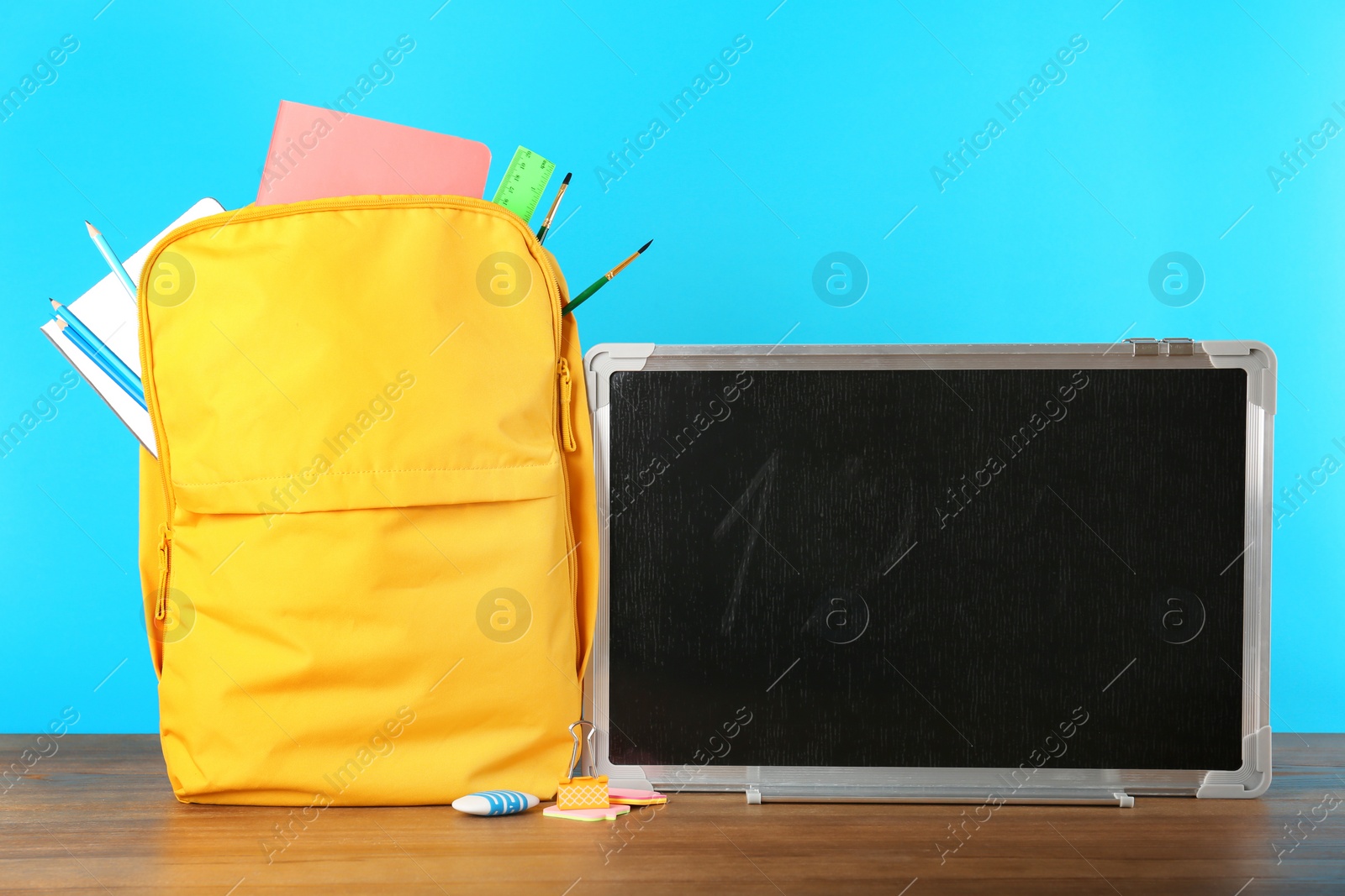 Photo of Small chalkboard and backpack with different school stationery on table