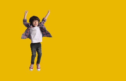 Happy boy jumping on golden background, space for text