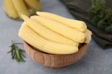 Photo of Tasty fresh yellow baby corns in bowl on grey table