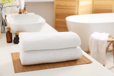 Photo of Stacked soft towels on white table in bathroom