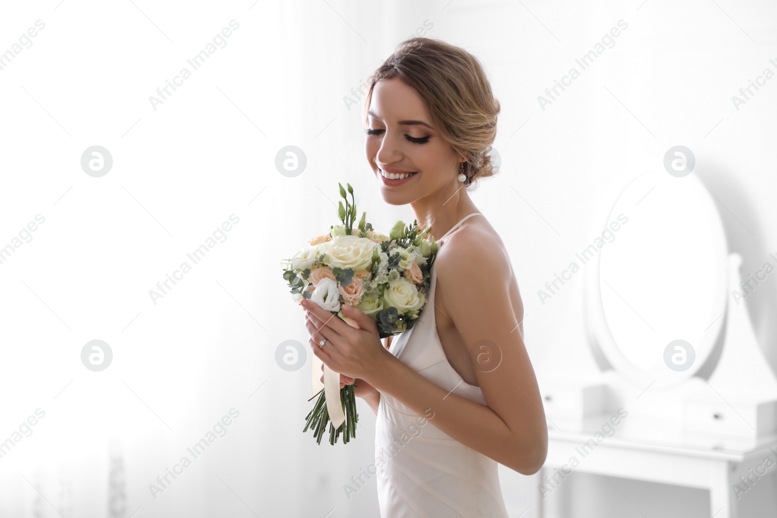 Photo of Young bride with beautiful wedding bouquet in room