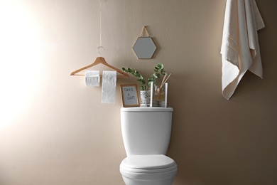 Photo of Decor elements, necessities and toilet bowl near beige wall. Bathroom interior