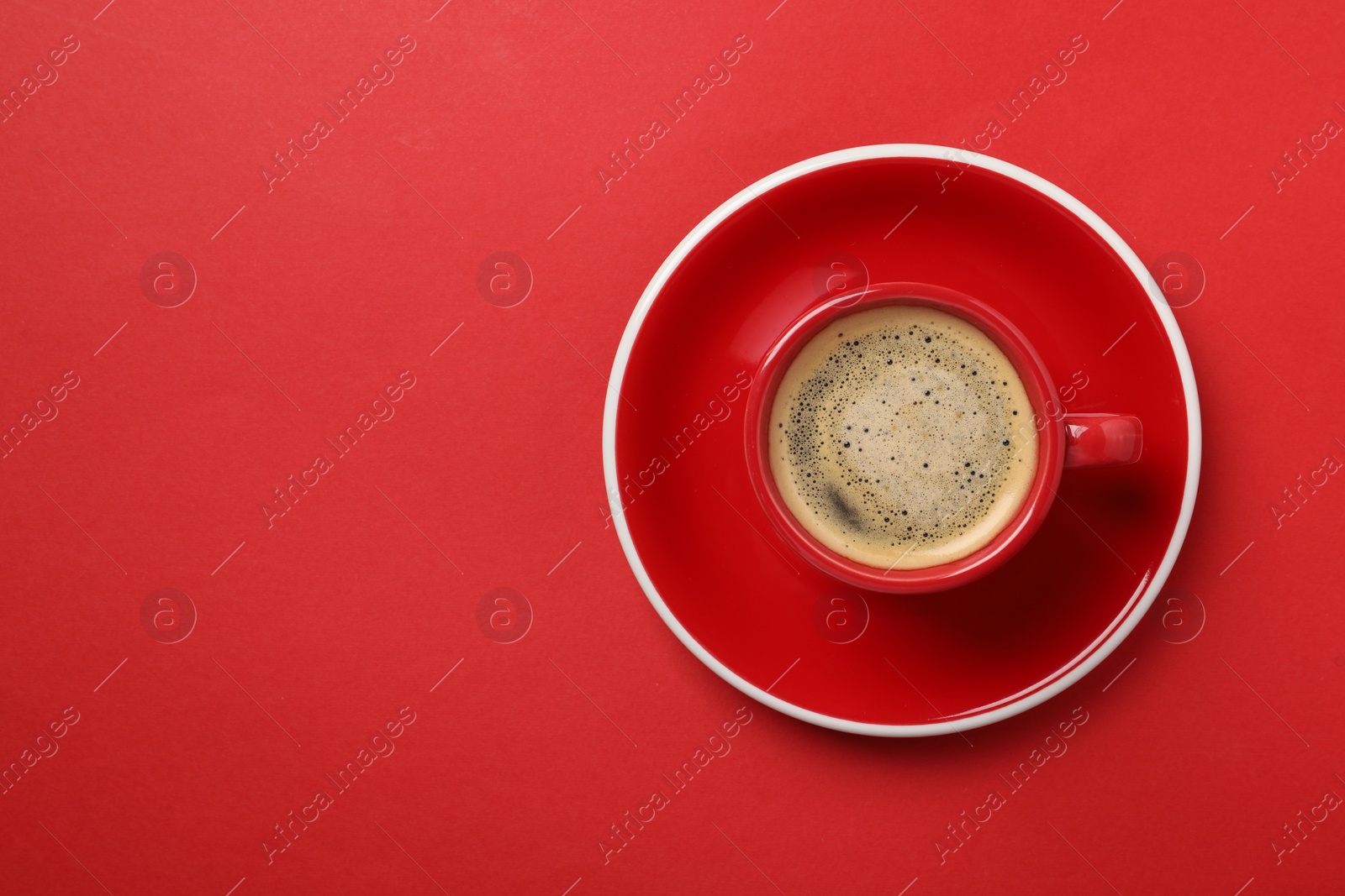 Photo of Tasty coffee in cup on red background, top view. Space for text