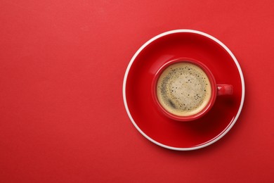 Photo of Tasty coffee in cup on red background, top view. Space for text