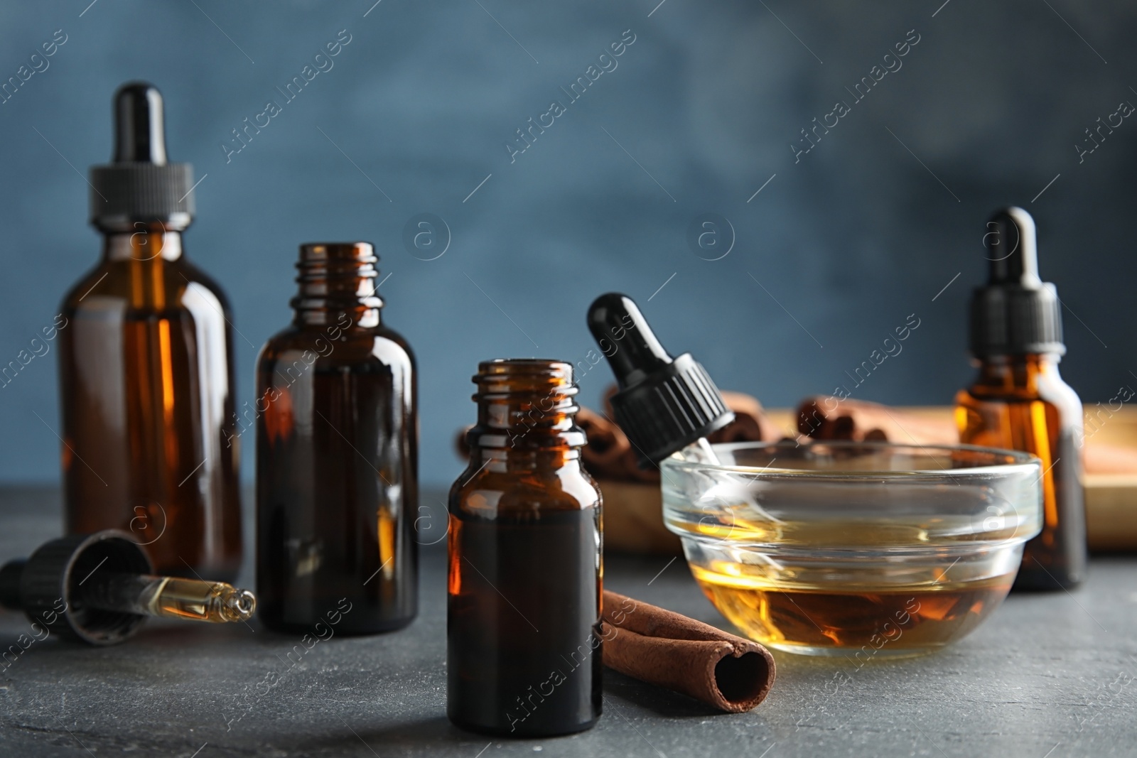 Photo of Composition with cinnamon essential oil on table against blue background