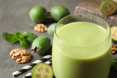 Photo of Fresh feijoa smoothie in glass on grey table, closeup with space for text