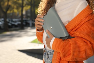 Photo of Young African American woman with stylish waist bag on city street, closeup. Space for text