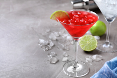 Tasty red alcoholic cocktail in martini glass on light grey table. Space for text