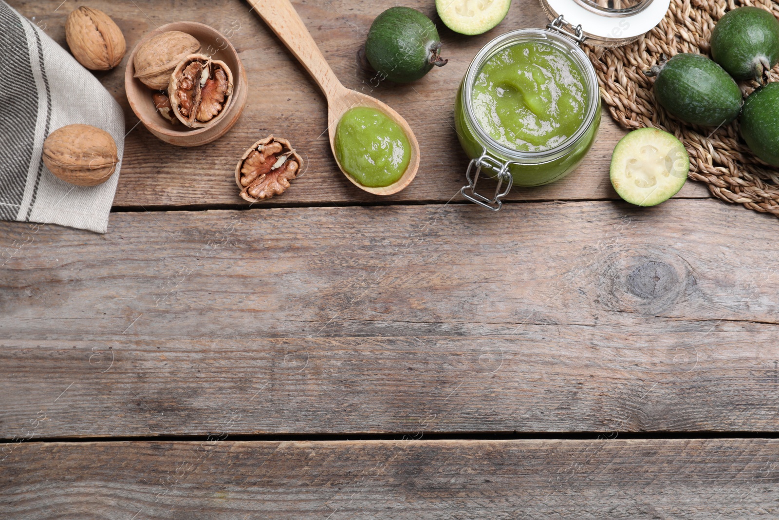 Photo of Feijoa jam and fruits on wooden table, flat lay. Space for text